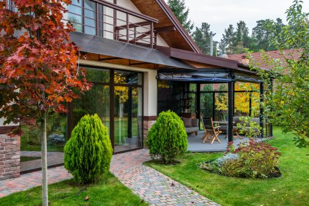 Grădina unei vile de oraș amenajată modern, cu plante decorative, mobilier exterior și atmosferă relaxantă.